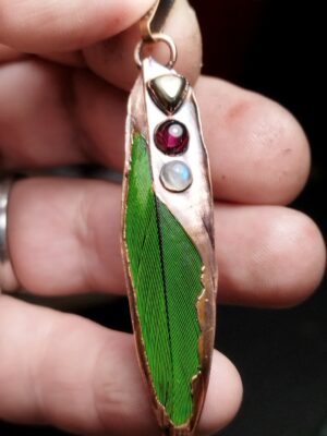 „Hlas z větru“ 🌀 - Měděný talisman Pírko papouška – ručně vyráběný šperk s pyritem, granátem a měsíčním kamenem